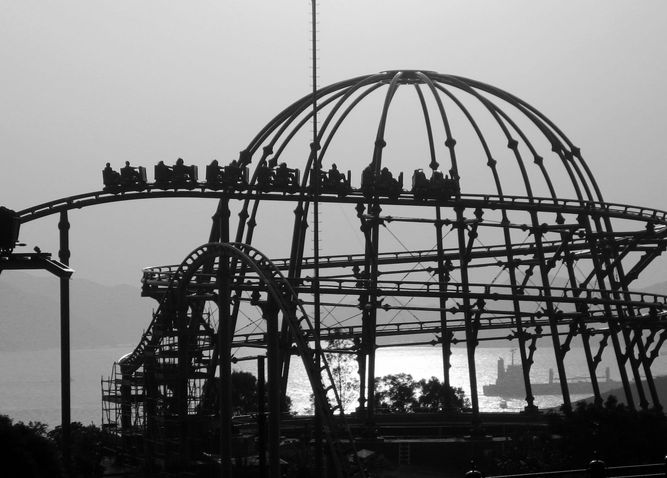 Small rollercoaster in silhouette with cars on the way down. 