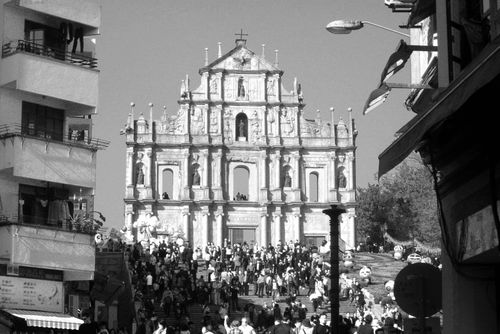 Front steps and facade of St. Paul's Cathedral in Macau surrounded by local buildings.