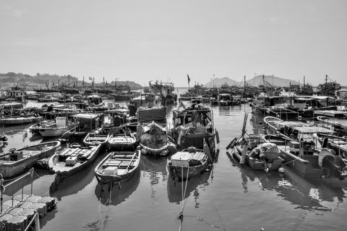 Small and large boats tied to one another in a tight harbor.