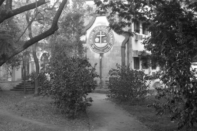 Concordia Seminary building with the seal on the wall through trees on the campus.