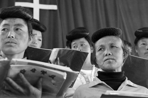 A group of women singing in the local village choir, holding music folders in front of them.