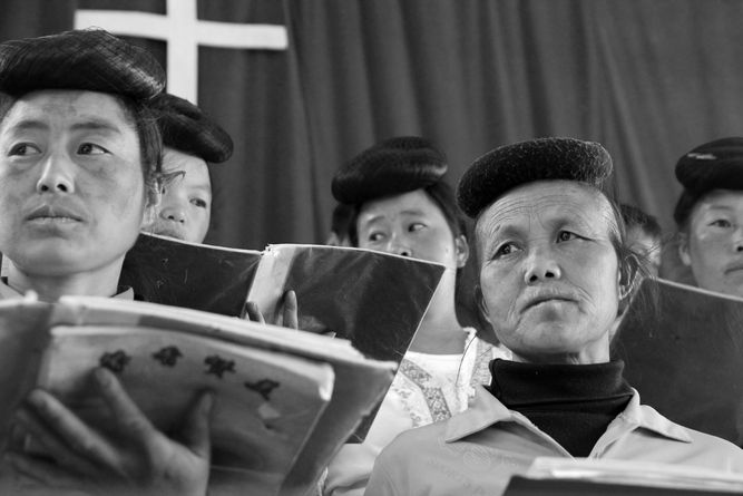 A group of women singing in the local village choir, holding music folders in front of them.