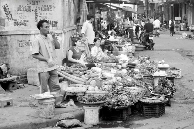 Vendors on a street corner, selling vegetables.