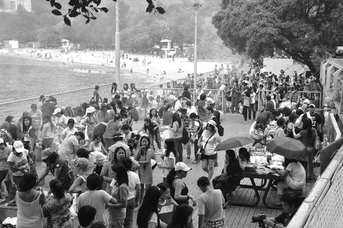 Crowds of people grilling near the beach on a Sunday afternoon.