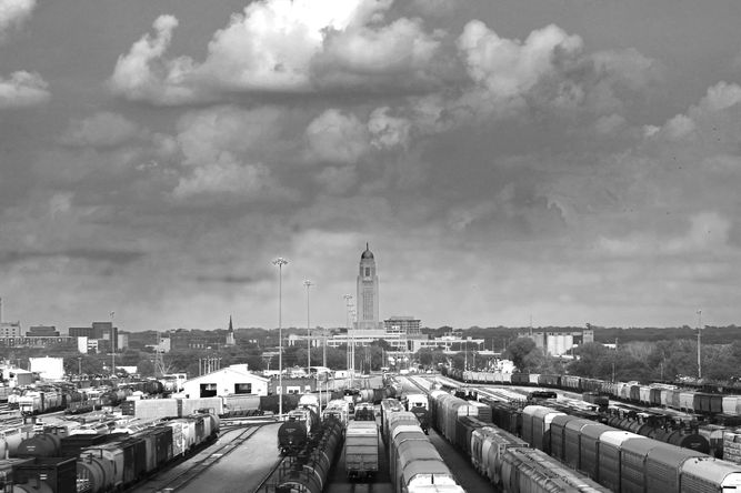 A train yard in the foreground with the Nebraska State Capitol building standing tall in the background.