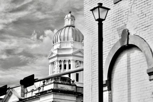 The courthouse on a street corner with streetlight and stoplight. 