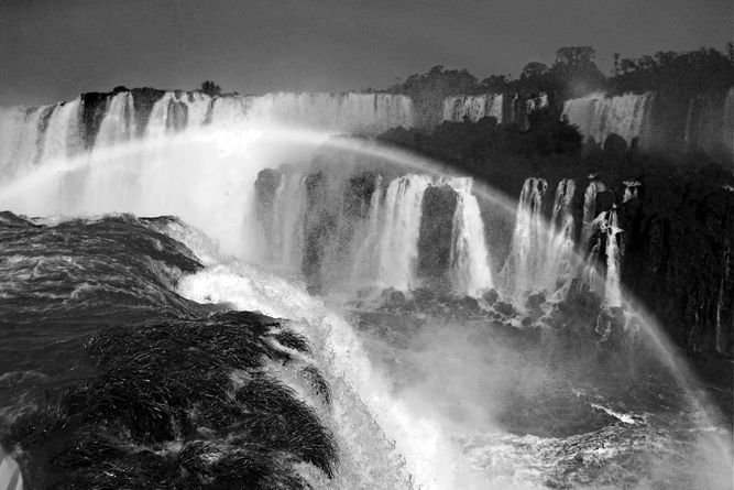 Numerous waterfalls with a rainbow appearing in the center of it all.