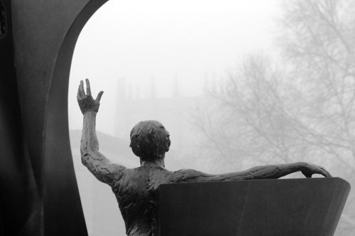 Close up of the Son of Man Be Free statue with Weller tower faintly visible in the morning fog.